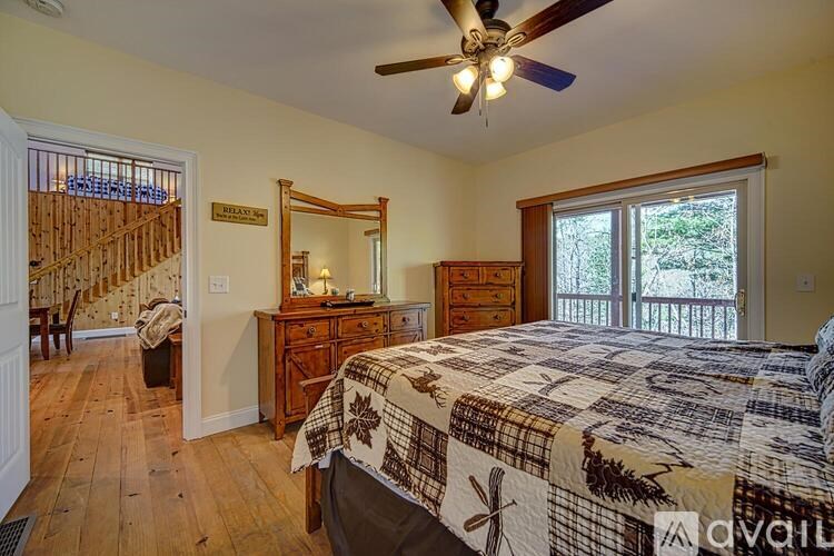 A bedroom with a bed, dresser, mirror, and a window with a view of trees.