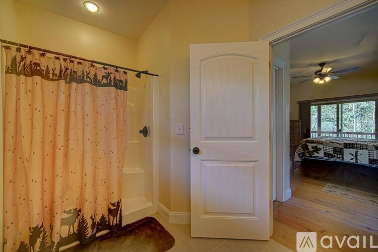 A room with a white door and a window with a view of trees outside.