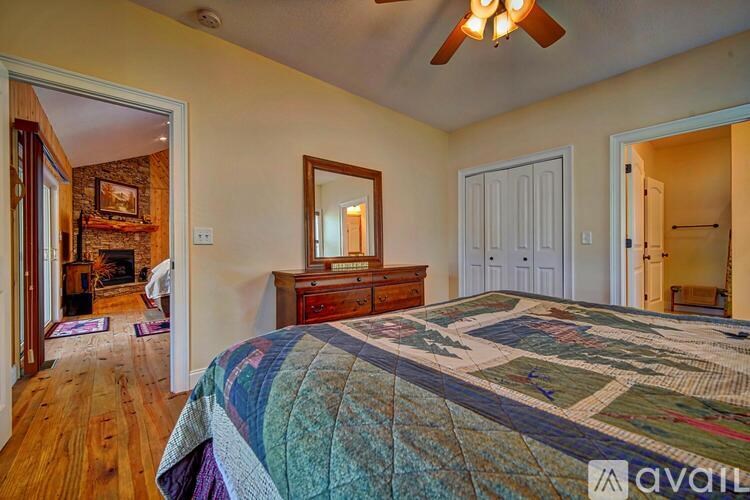 A bedroom with a bed, dresser, mirror, and a ceiling fan.