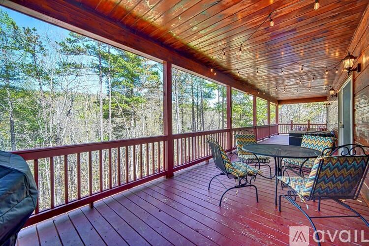 A wooden deck with a table and chairs overlooking a forest.