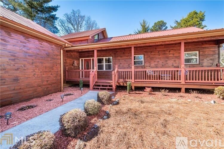 A wooden house with a red roof and a porch.