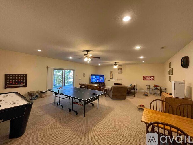 A room with a ping pong table, a couch, a TV, and a clock on the wall.
