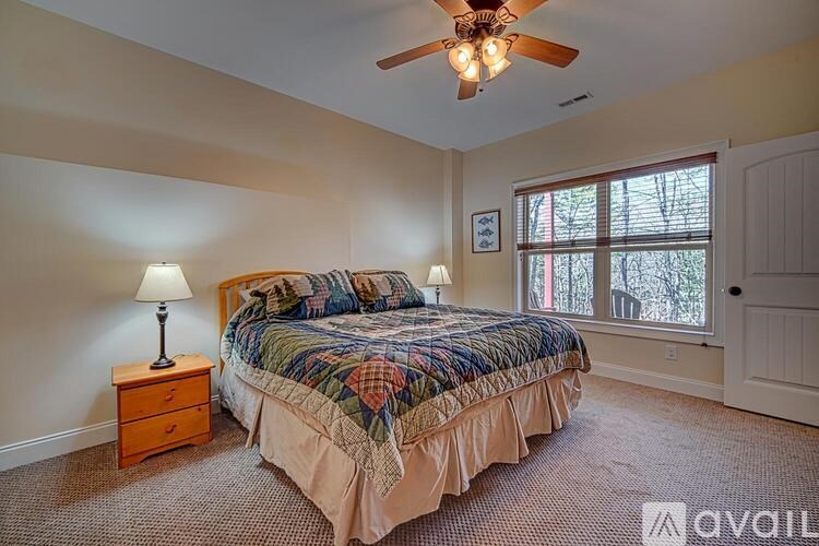 A bedroom with a bed, a ceiling fan, and a window.