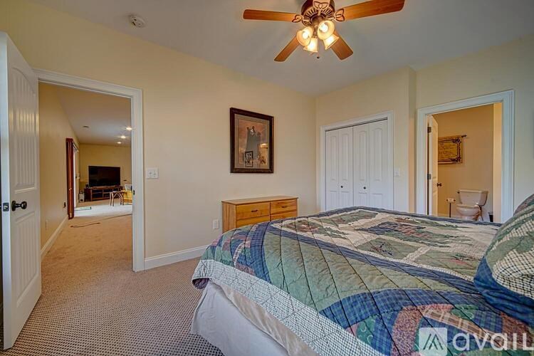 A bedroom with a bed, a ceiling fan, and a picture on the wall.