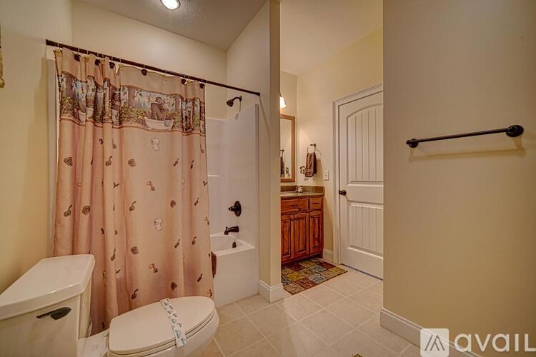 A bathroom with a toilet, a sink, and a shower with a pink shower curtain.