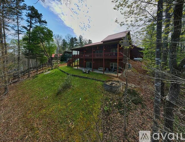 A house with a red roof is surrounded by trees and has a yard with a fence.