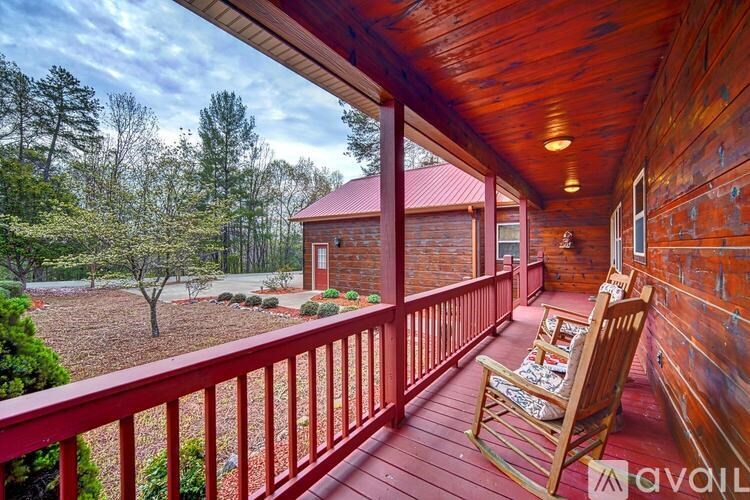 A wooden porch with a red railing and a rocking chair.