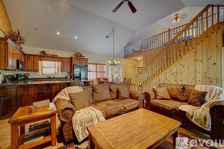 A living room with a staircase and a kitchen area.