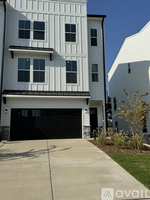 A two-story white house with a black garage door.