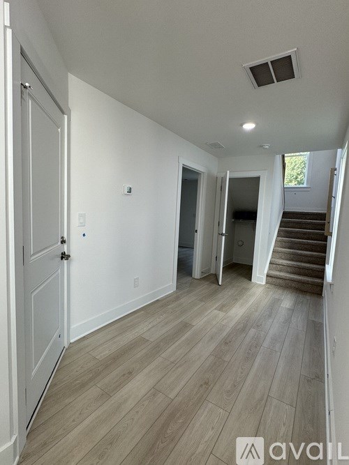 A hallway with a white door and wooden flooring.