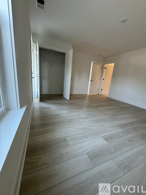 A spacious room with wooden flooring and white walls.