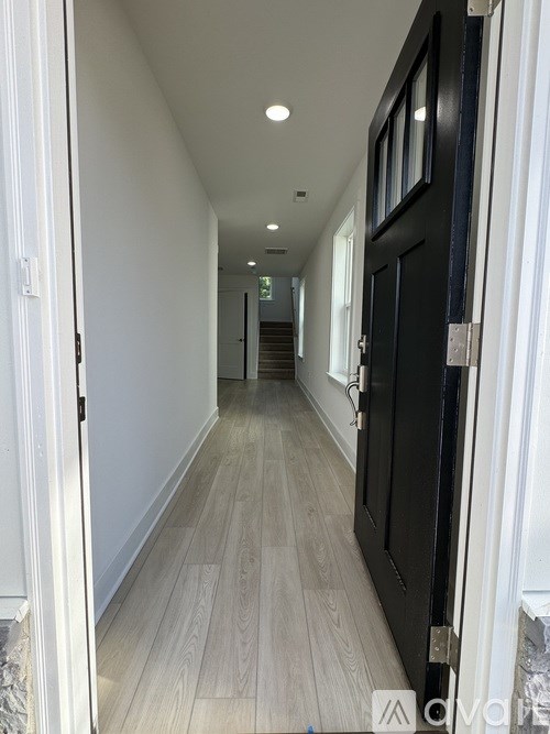 A long hallway with a black door on the right.