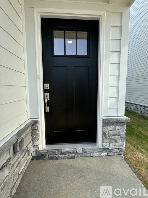 A black door with a glass window is set in a white frame.