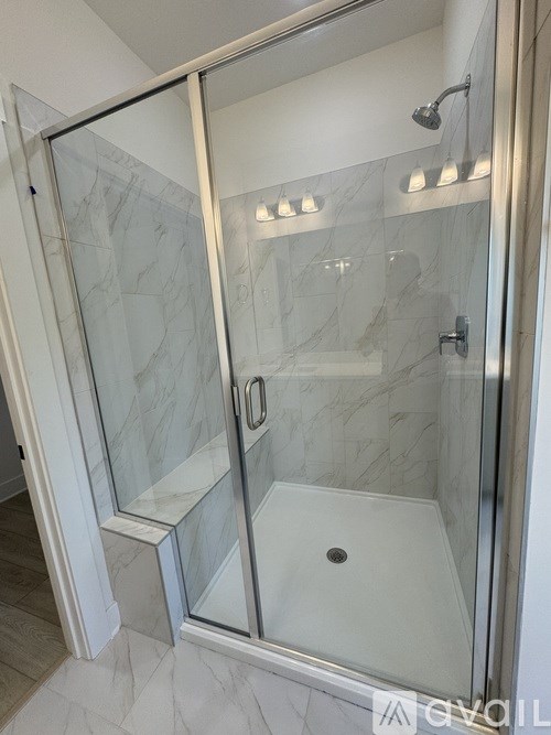 A glass shower stall with a glass door and a glass shower head.