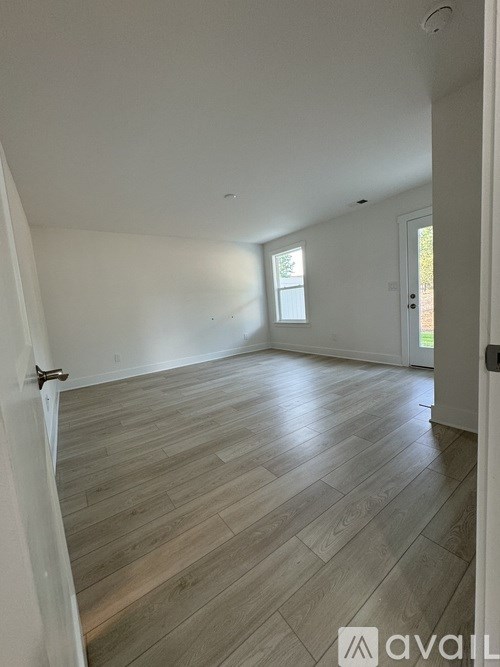 A room with wooden flooring and a door on the right.