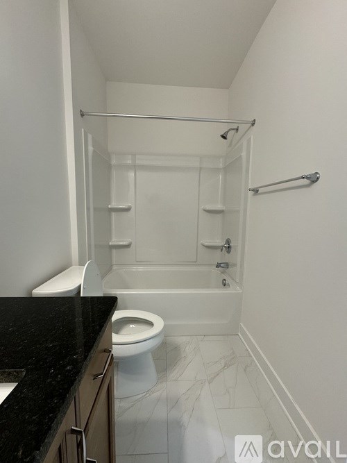 A white toilet sits in a bathroom with a black counter top.