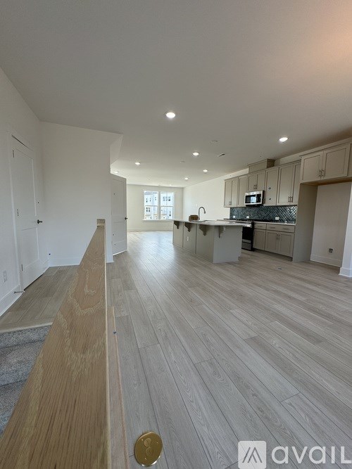 A spacious kitchen and living room with wooden flooring and white walls.