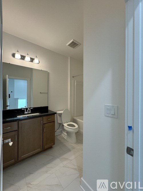 A bathroom with a toilet, sink, and mirror.