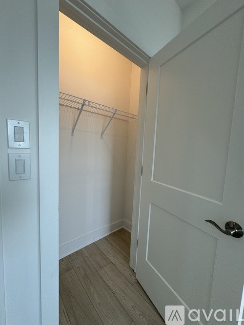 A white door with a handle and a small square light switch on the wall.