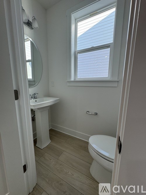 A small bathroom with a toilet, sink, and window.