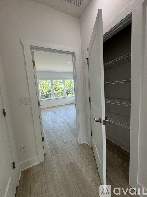 A hallway with a door open to a closet and a window.