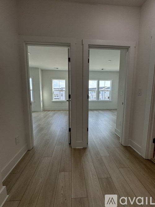 A room with wooden floors and two open doors.