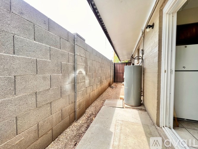 A long, narrow hallway with a brick wall on one side and a metal container on the other.
