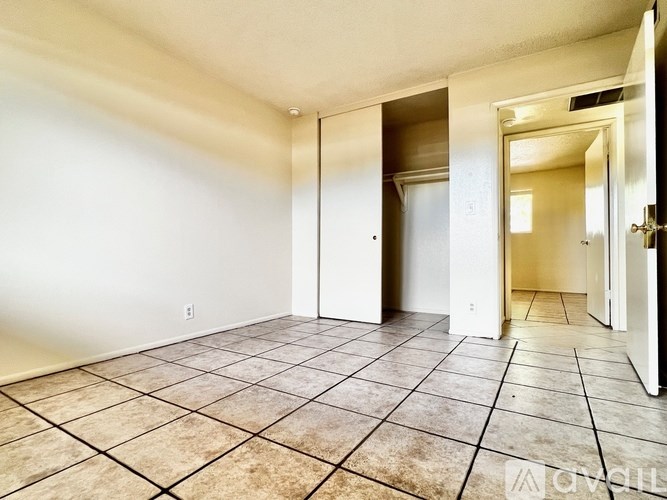 A spacious room with tiled flooring and white walls.