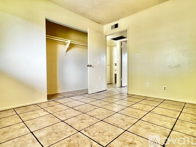 A hallway with tiled floors and two doors, one of which is open.