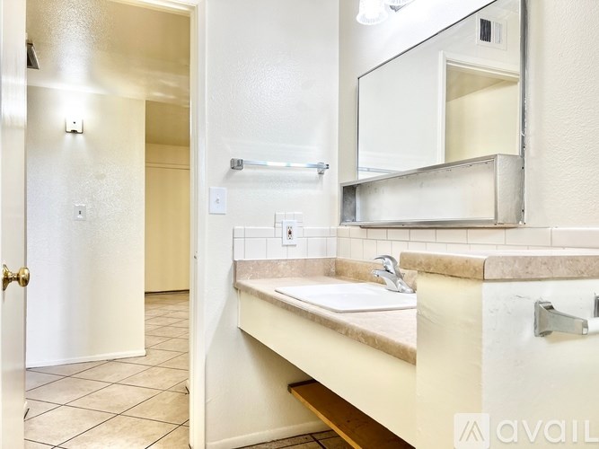A bathroom with a sink, mirror, and tiled floor.