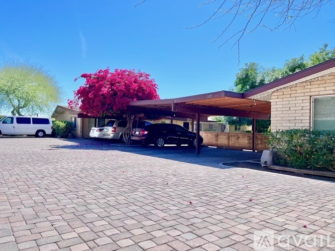 A brick driveway leads to a house with a covered entrance.