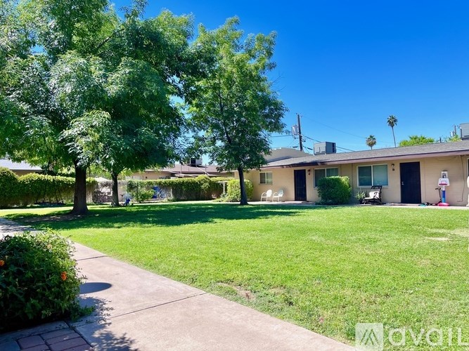A house with a green lawn and trees in front of it.