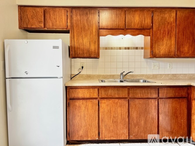 A kitchen with wooden cabinets and a white refrigerator.