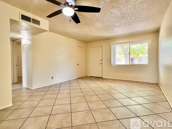 Empty room with a ceiling fan and tile flooring.