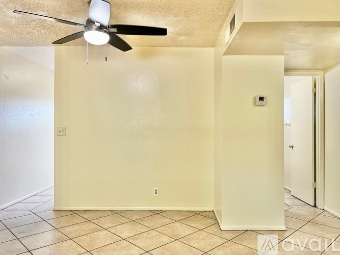 A room with a ceiling fan and tile flooring.