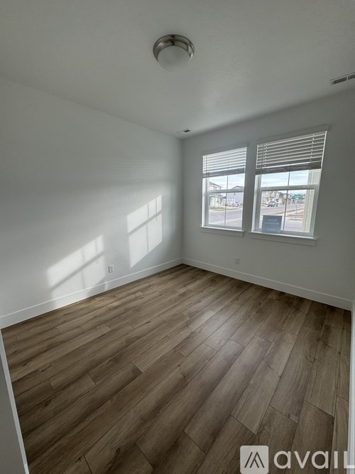 A room with wooden flooring and a window with blinds.