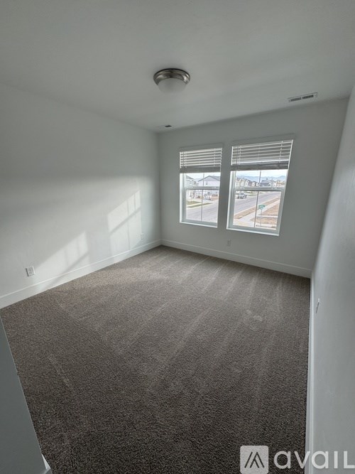 A carpeted room with a window overlooking a street.