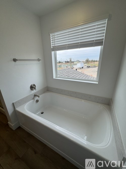 A white bathroom with a tub and a window.