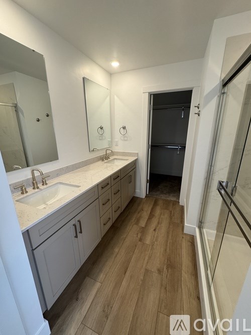 A bathroom with a sink, mirror, and wooden floors.
