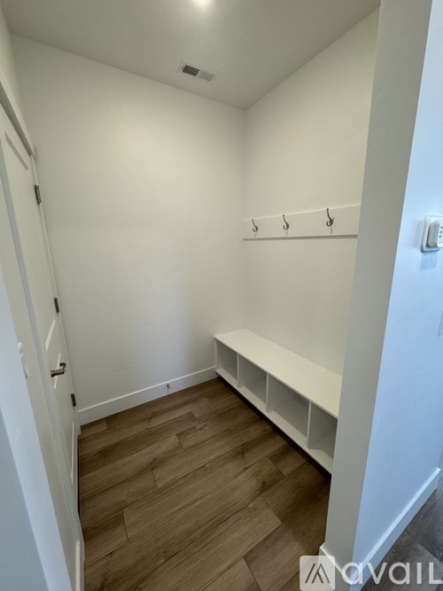 A white hallway with a bench and coat rack.