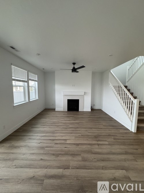 A spacious room with a fireplace and a staircase.