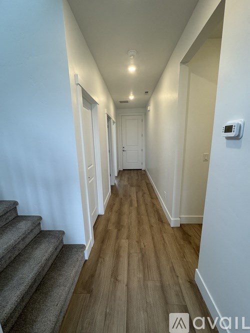 A long hallway with a staircase on the left and a door on the right.