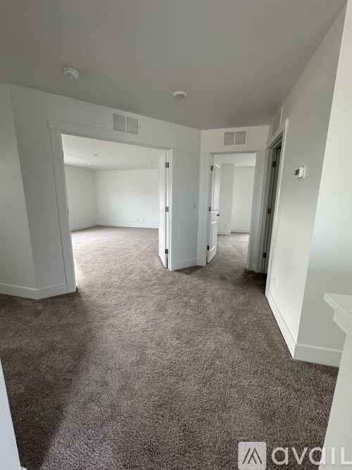 A carpeted room with a doorway leading to another room.