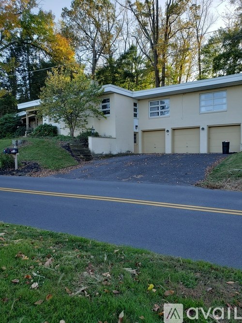 A house with a white and beige exterior is situated on a street with a yellow line.