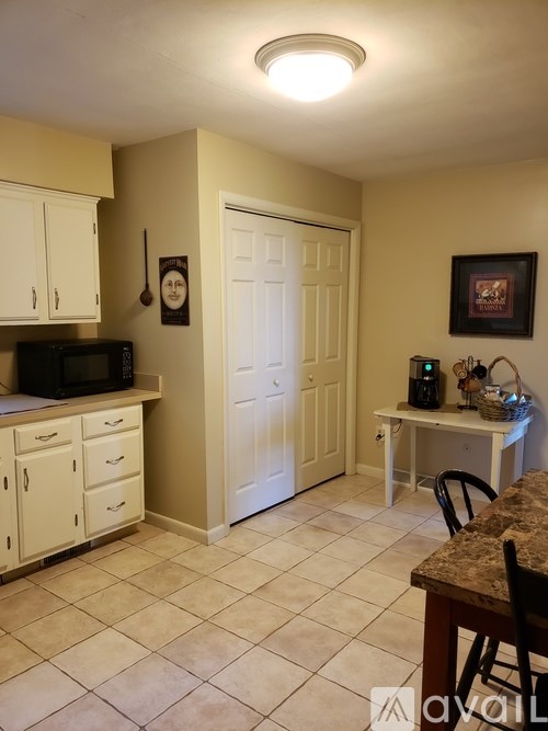 A kitchen with a microwave, cabinets, and a fridge.