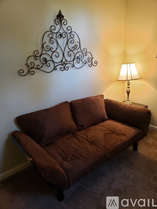 A brown couch sits in front of a wall with a metal decoration above it.