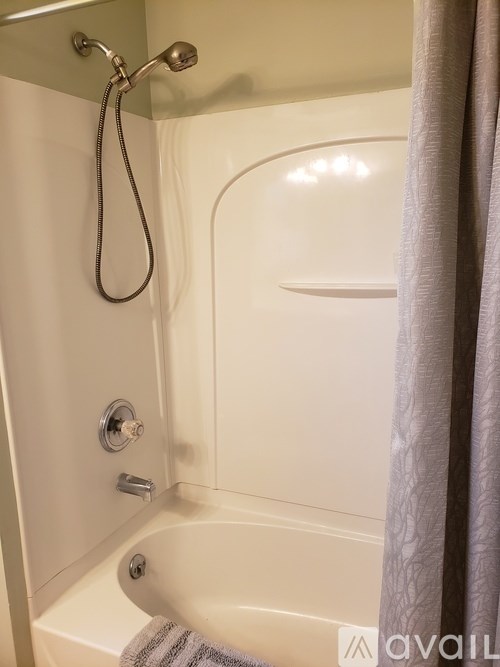 A bathroom with a white tub and a shower head.