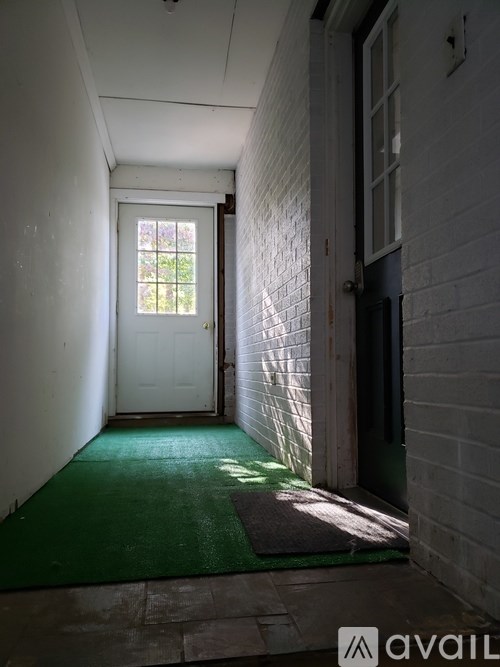 A hallway with a green carpet and white walls.