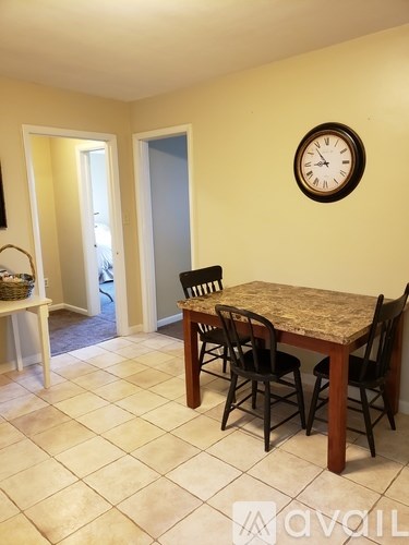 A dining room with a table and chairs and a clock on the wall.