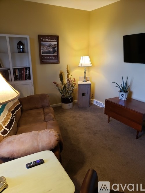 A living room with a brown couch, a white table, and a lamp.